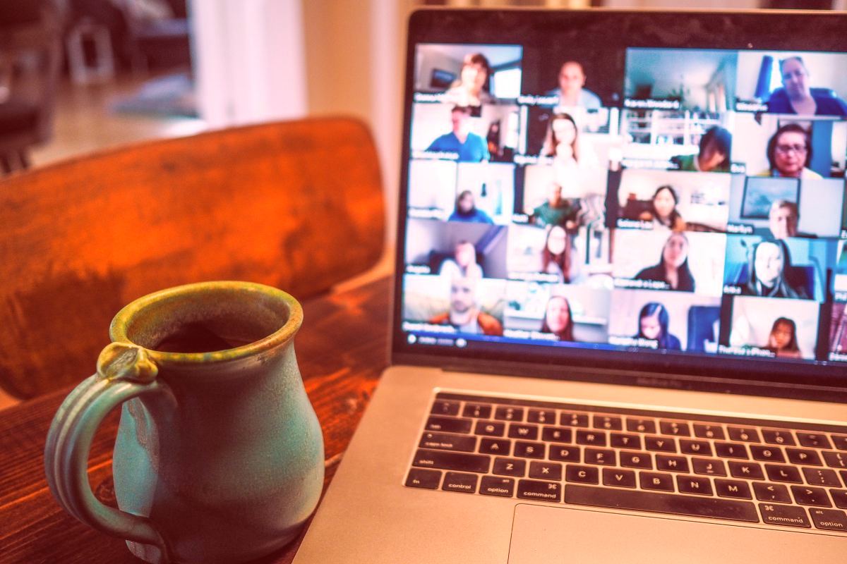 People on a zoom call on a laptop with a cup of coffee